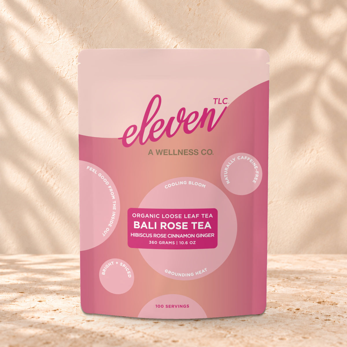 Eleven TLC Bali Rose Loose Leaf Tea 360g stand-up pouch on travertine stone against a warm cream plaster wall, lit from the left with a soft shadow to the right.