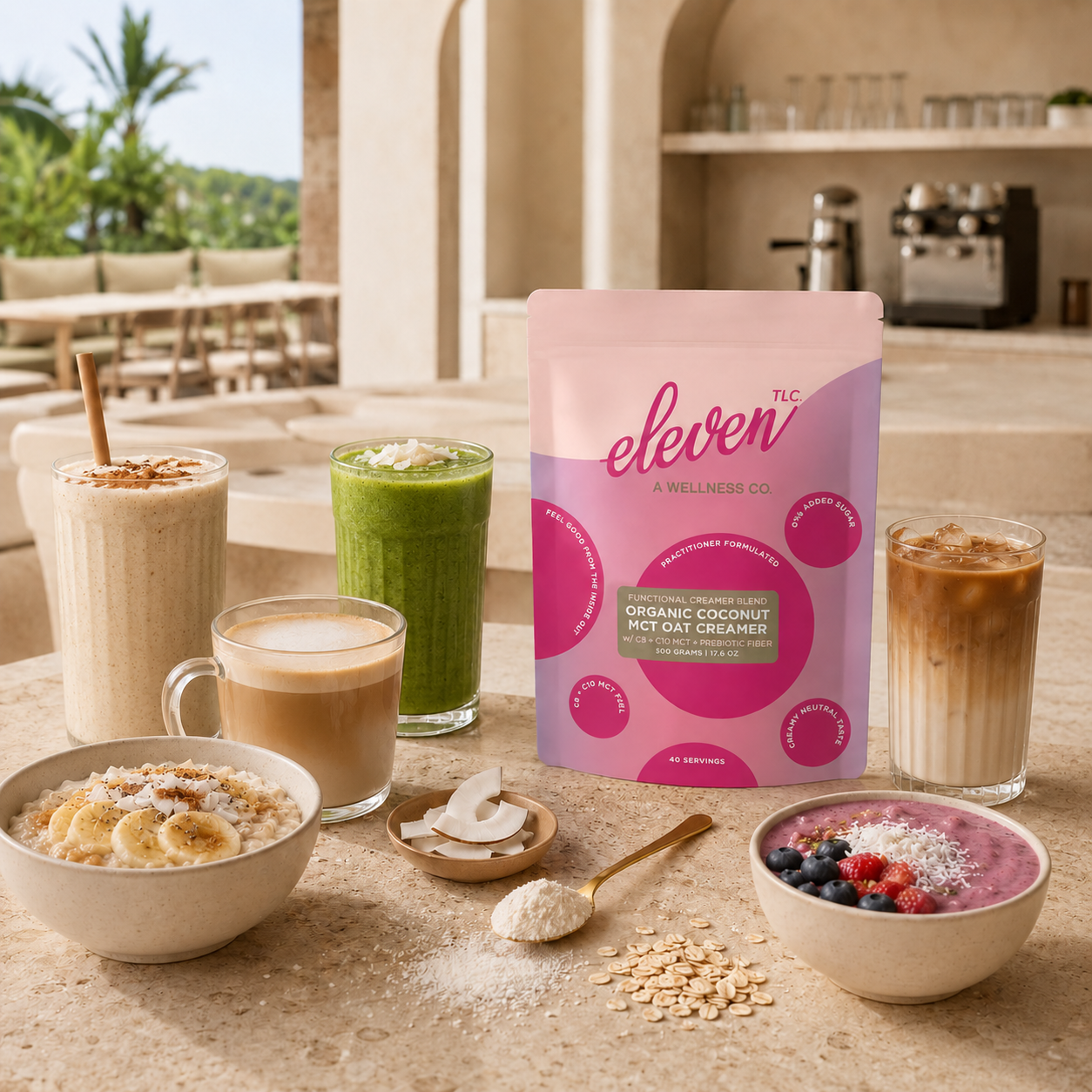 Lifestyle staging on a stone terrace featuring the Eleven TLC 500g organic coconut oat mct creamer pouch as the central component, surrounded by a variety of prepared morning beverages including frothy matcha, coffee, and a berry-topped breakfast bowl. The setting includes raw coconut and oat accompaniments in a warm, natural, open-air environment, reinforcing the brand's daily signal workflow in an elevated culinary context.