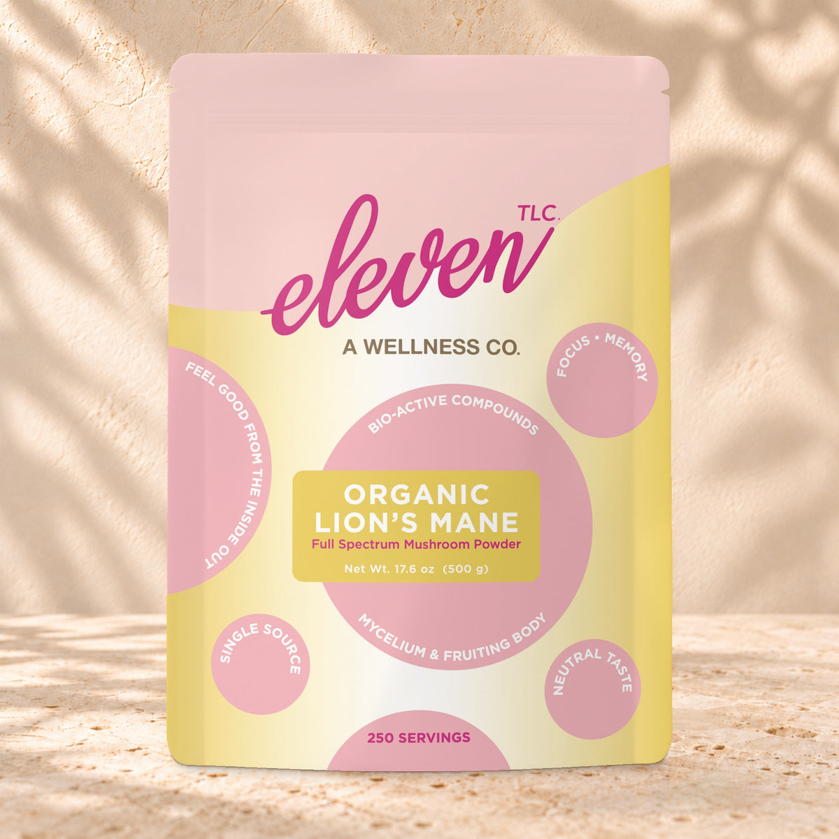 Front view of an Eleven TLC Lion’s Mane Mushroom Powder 500g pouch on warm travertine against a cream plaster wall with botanical shadows.