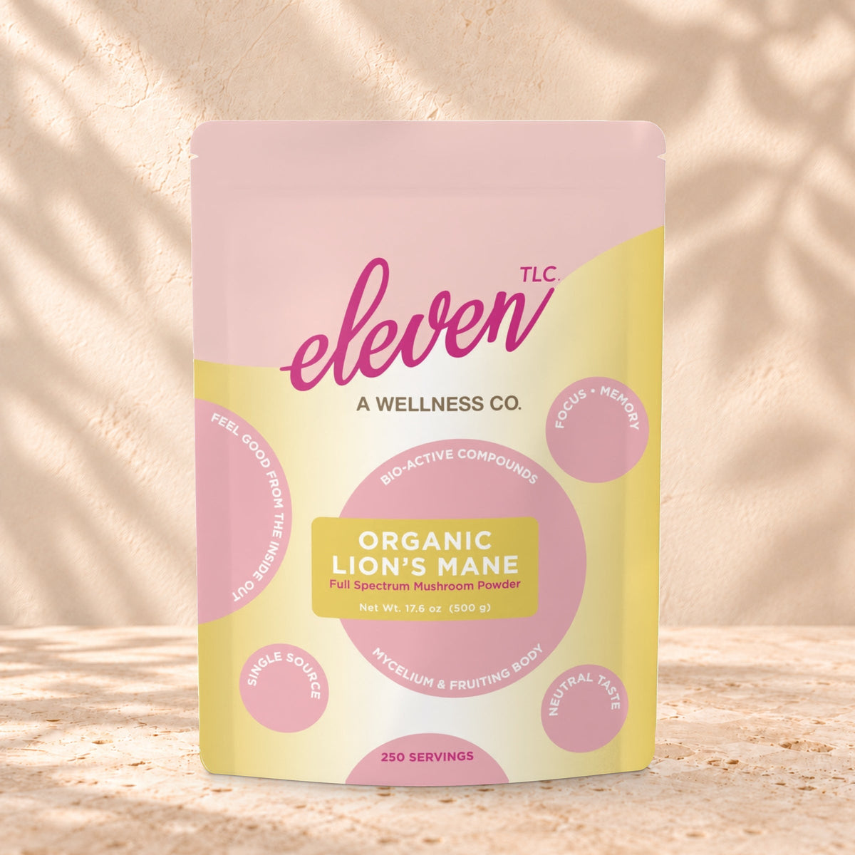Eleven TLC Organic Lion's Mane Mushroom Powder 500g stand-up pouch on travertine stone against a warm cream plaster wall, lit from the left with a soft shadow to the right.