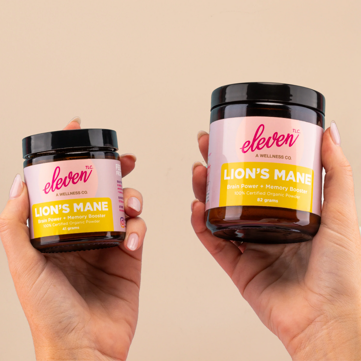 Two hands holding Eleven TLC Organic Lion's Mane Mushroom Powder in the 41g and 82g amber glass jars to compare sizes.