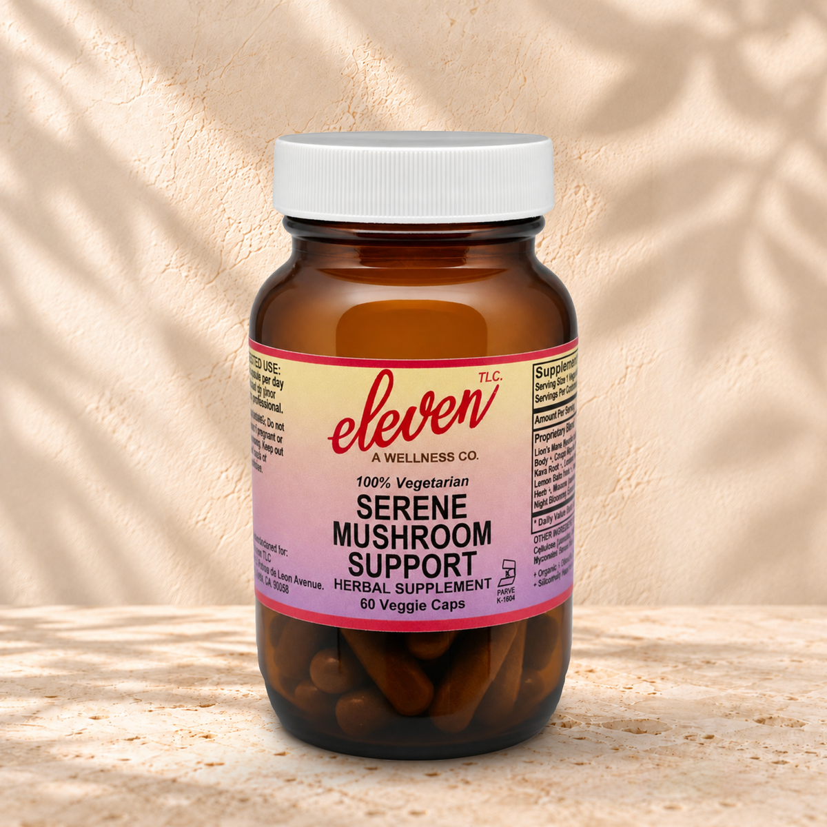 Eleven TLC Serene Mushroom 60-count capsule bottle with a white lid on warm travertine against cream plaster, with soft contact shadows.