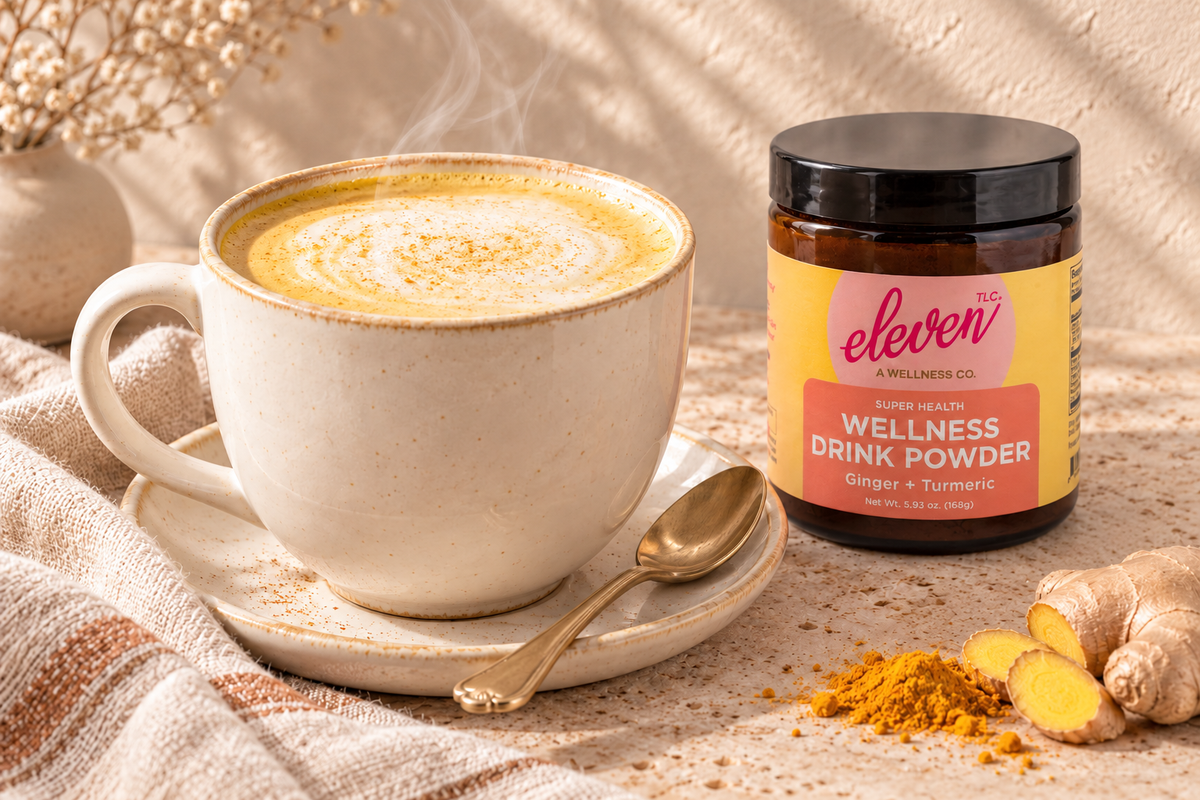 Steaming Ginger + Turmeric latte with softly frothed milk beside the Eleven TLC 168g jar.