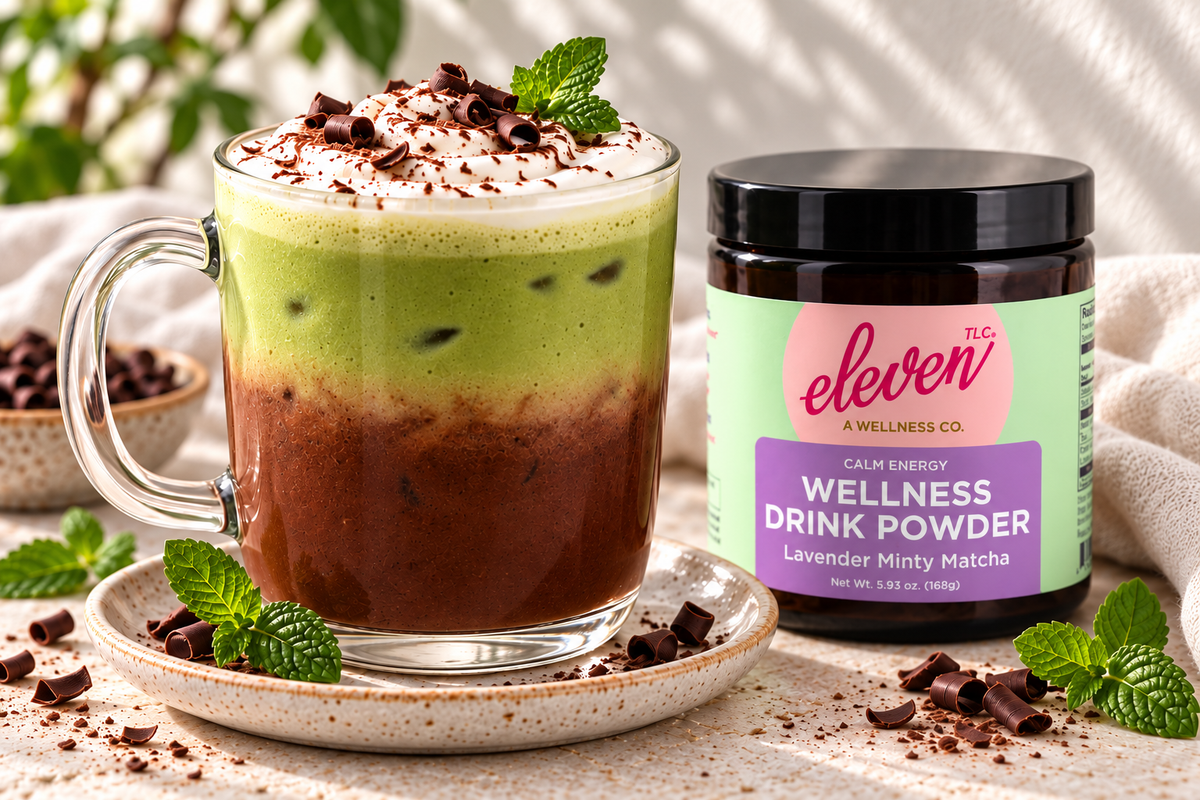 Layered cacao and mint matcha latte topped with cream, chocolate curls and mint beside an Eleven TLC Minty Lavender Matcha jar.