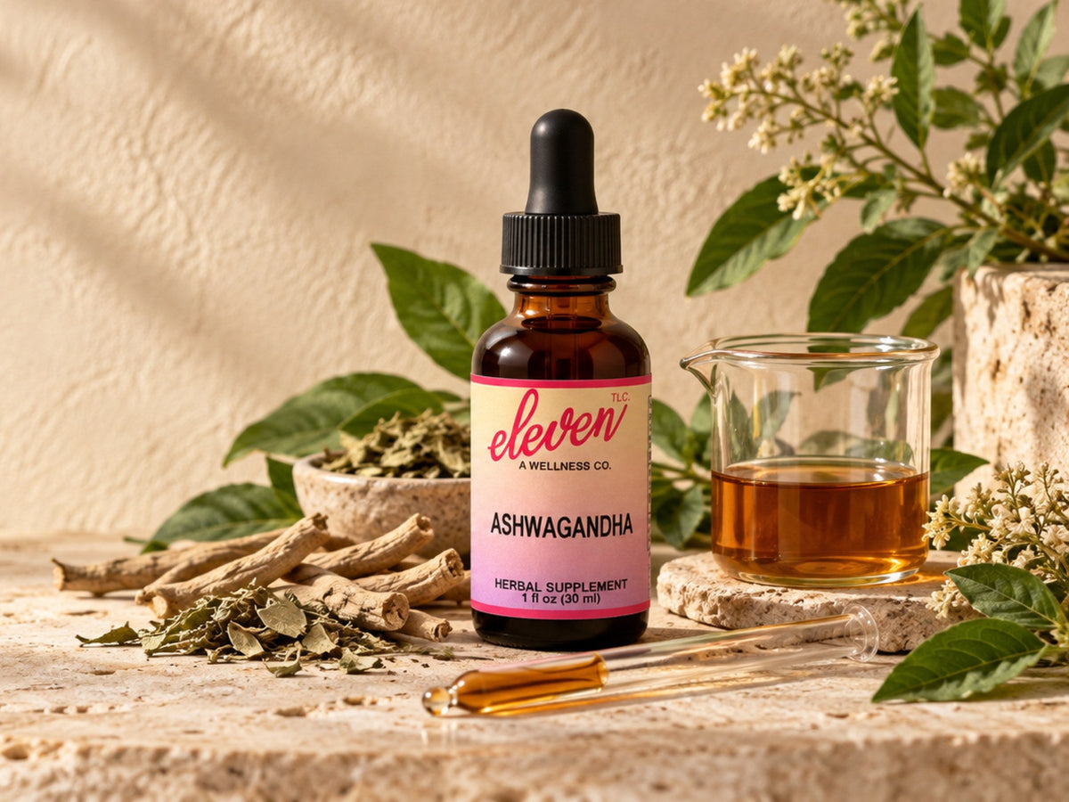 Eleven TLC Ashwagandha herbal supplement tincture in a 1 fl oz amber dropper bottle with dried ashwagandha root and leaves on travertine stone