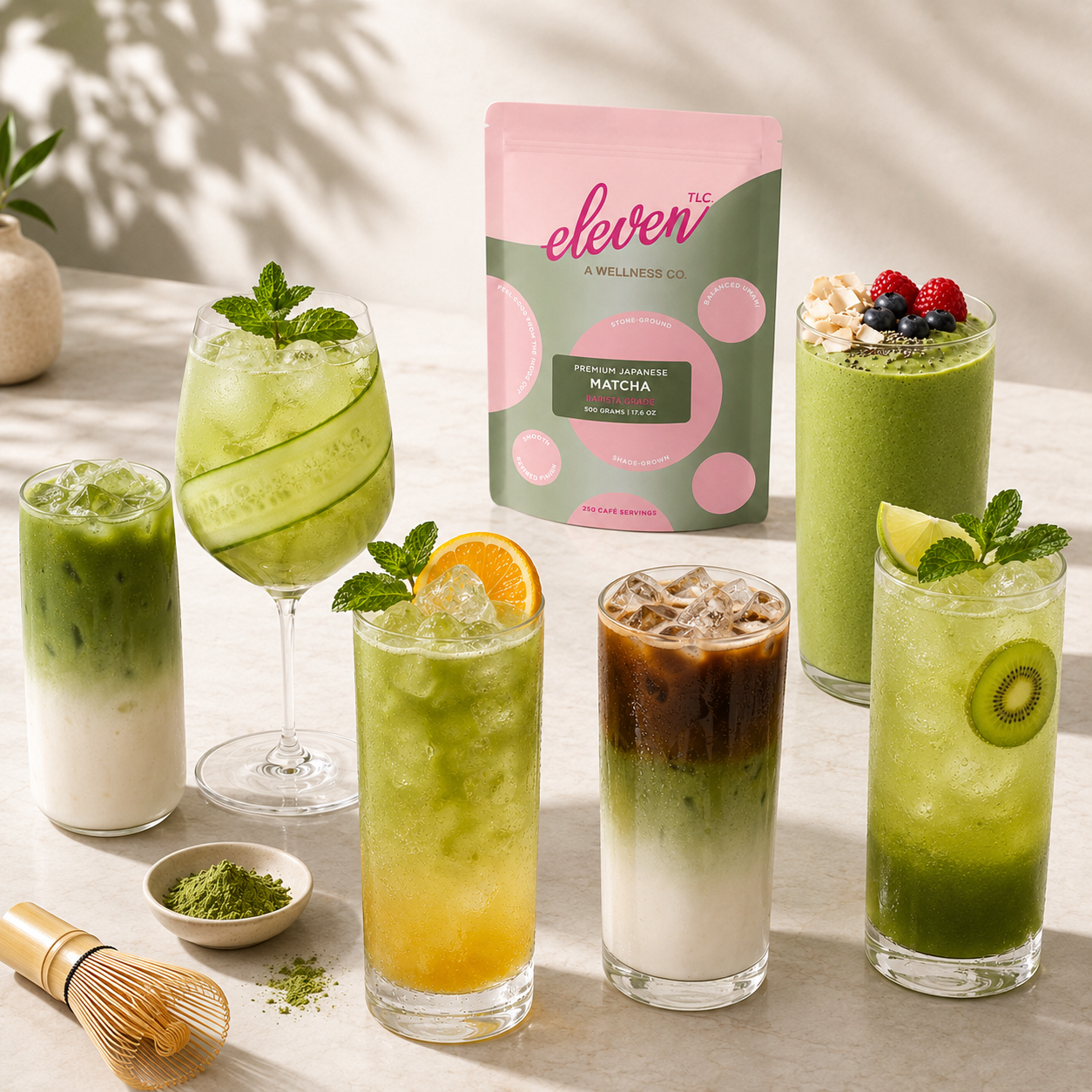 Eleven TLC Organic Japanese Barista Matcha Powder 500g pouch displayed next to a variety of prepared matcha lattes, iced matcha lemonade, and iced matcha coffee on a light surface.