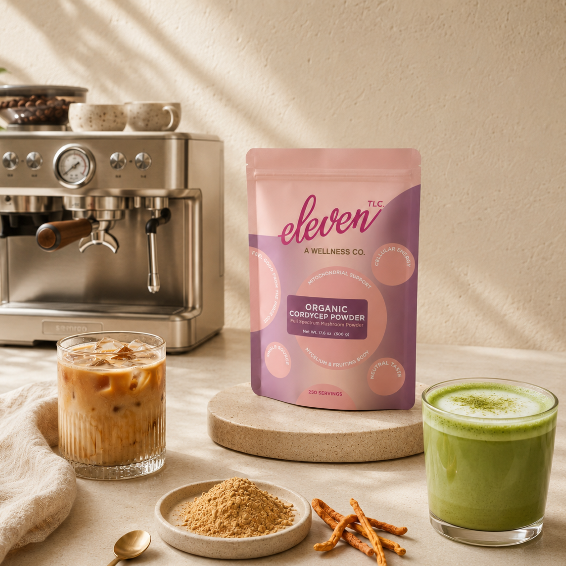 Eleven TLC Organic Cordyceps Powder 500g foodservice pouch displayed on a limestone countertop next to a commercial espresso machine, an iced cordyceps beverage, and a whisked matcha latte.