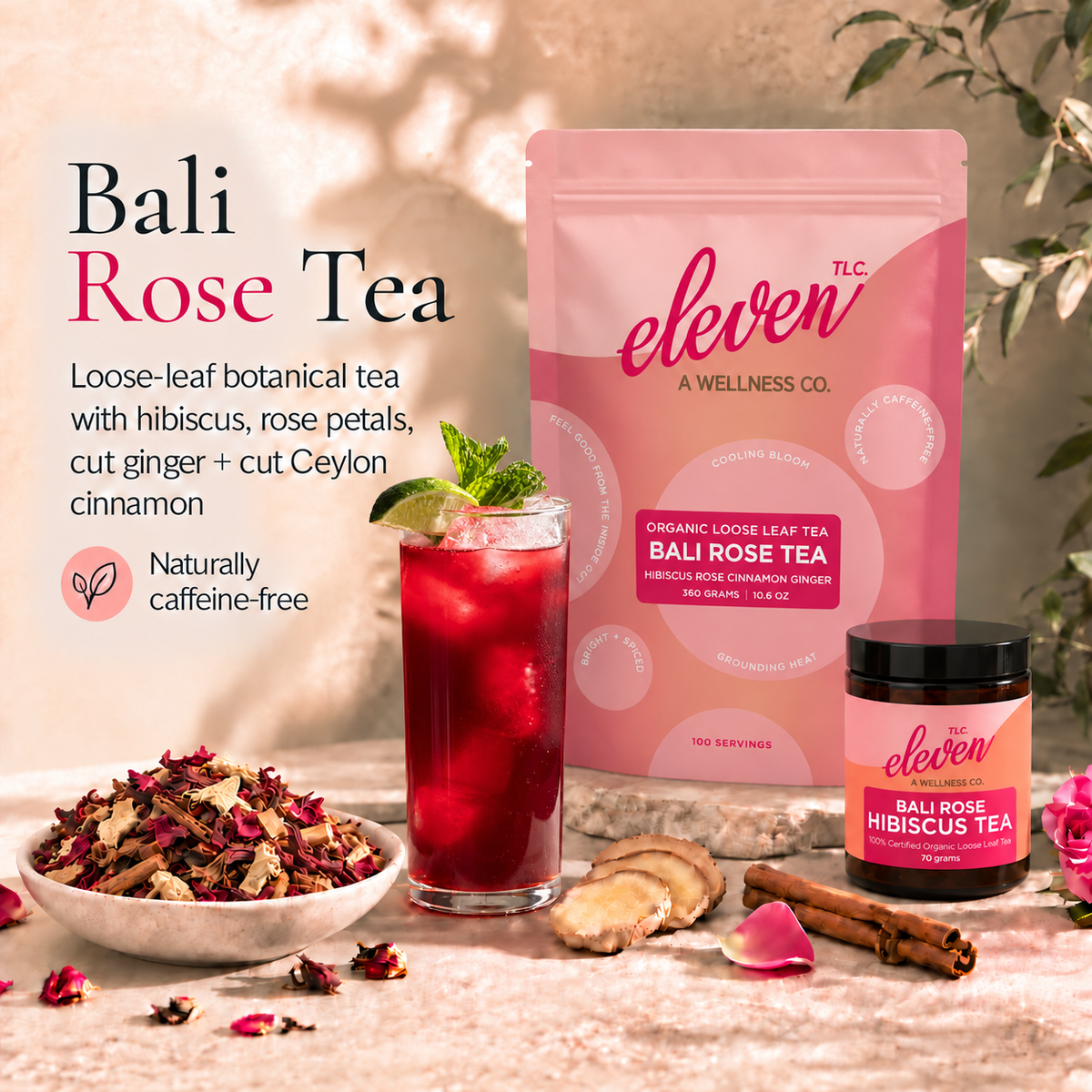 Eleven TLC Bali Rose Hibiscus Tea pouch and 70g jar beside ruby-red iced tea garnished with mint and lime, with loose-leaf botanicals on cream travertine.