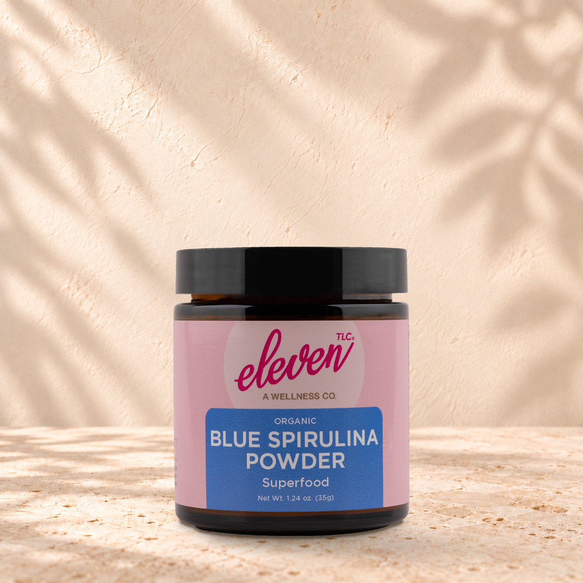 Eleven TLC Organic Blue Spirulina Powder, 35 g amber-glass jar, front label, travetine ground 