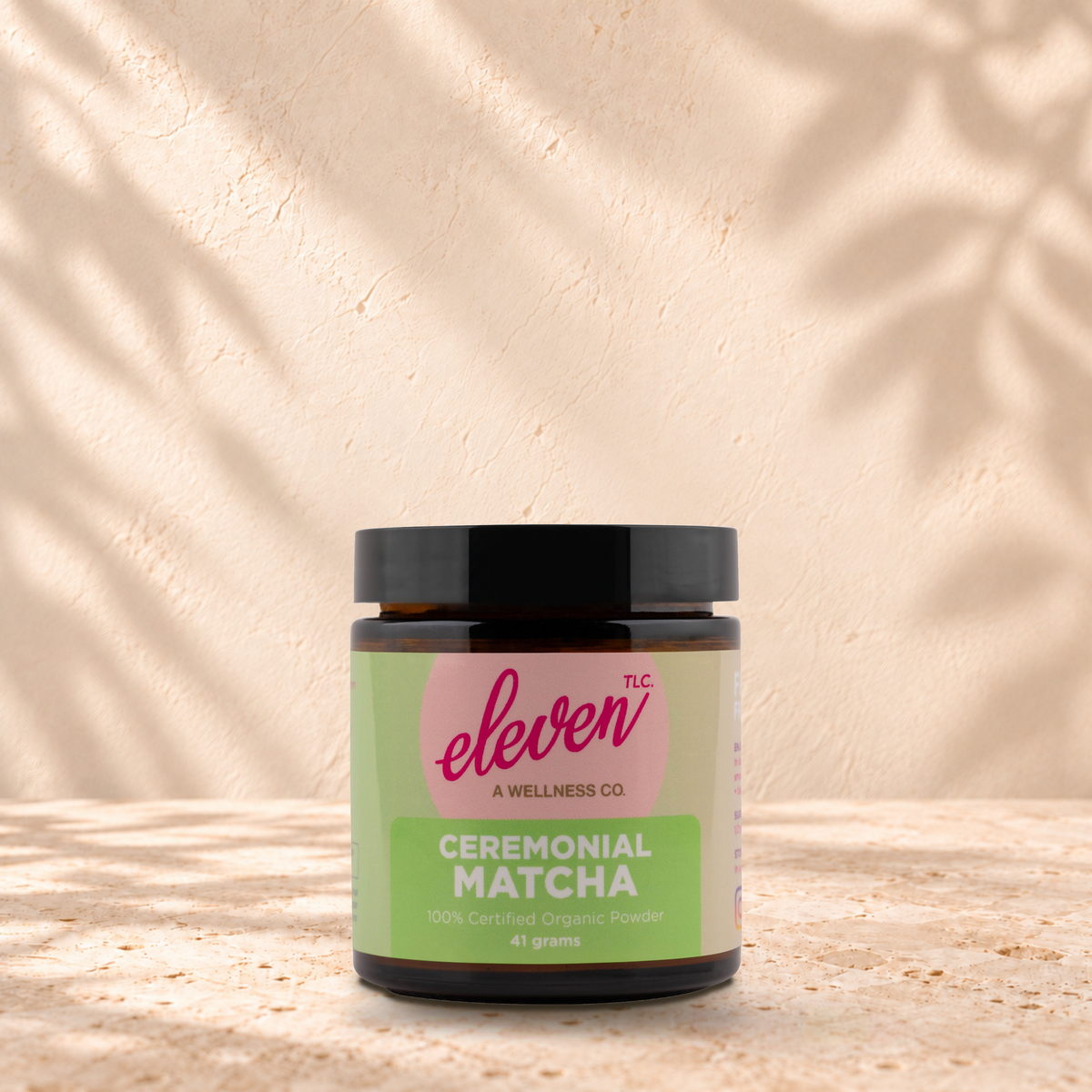 Eleven TLC Ceremonial Matcha 41g jar standing on a travertine ledge against warm plaster with a natural contact shadow.
