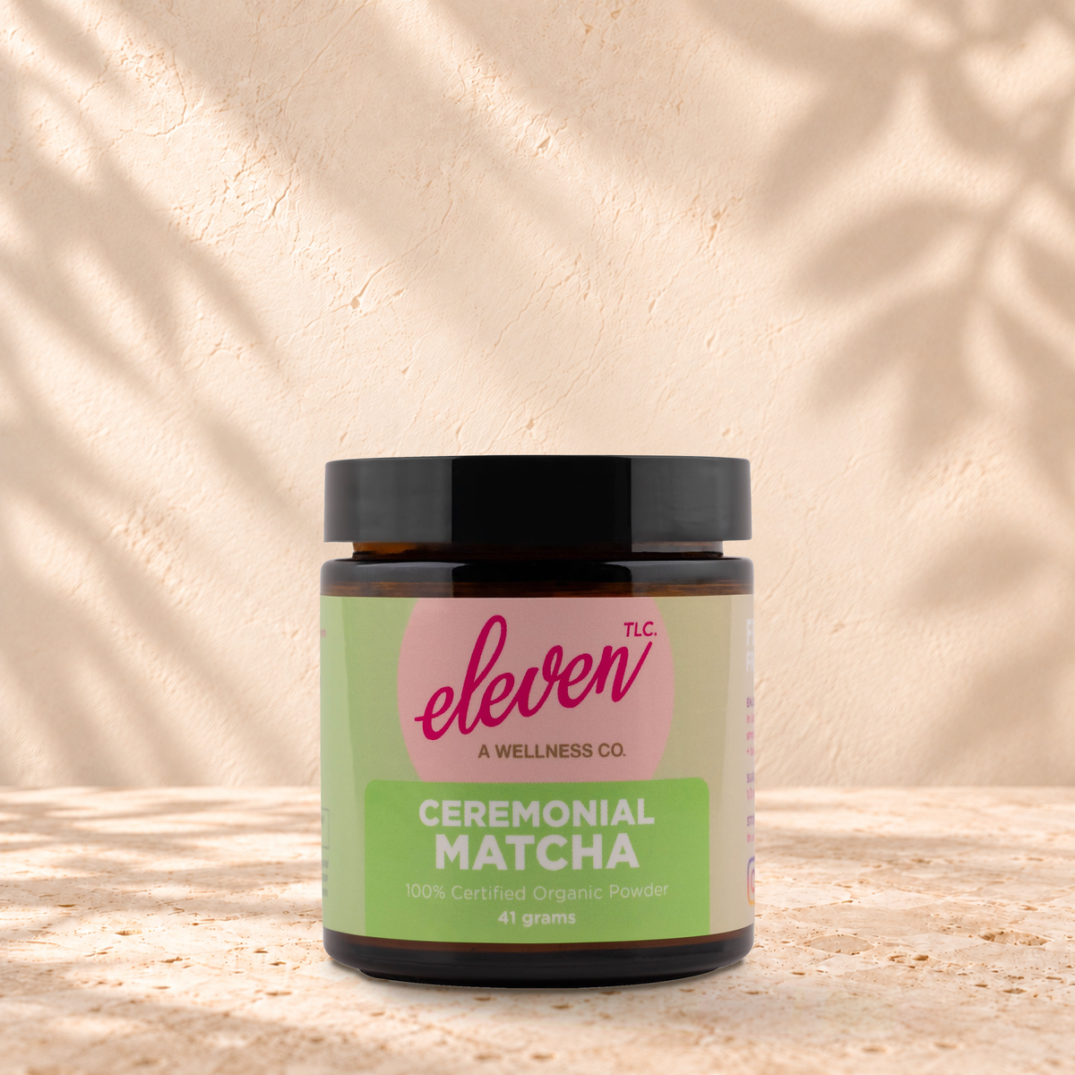Eleven TLC Ceremonial Matcha 41g jar standing on a travertine ledge against warm plaster with a natural contact shadow.
