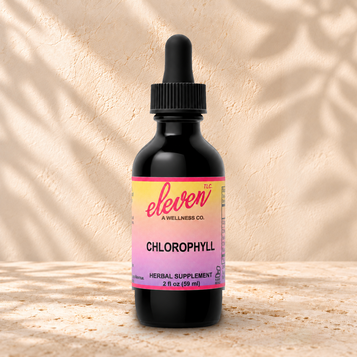 Eleven TLC Chlorophyll 2 fl oz tincture in a dark glass bottle with a black dropper on warm travertine against a cream plaster wall.