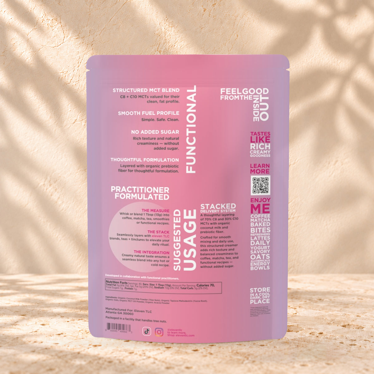 Back view of an Eleven TLC Coconut MCT Oat Creamer 500g pouch on warm travertine against a cream plaster wall with botanical shadows.