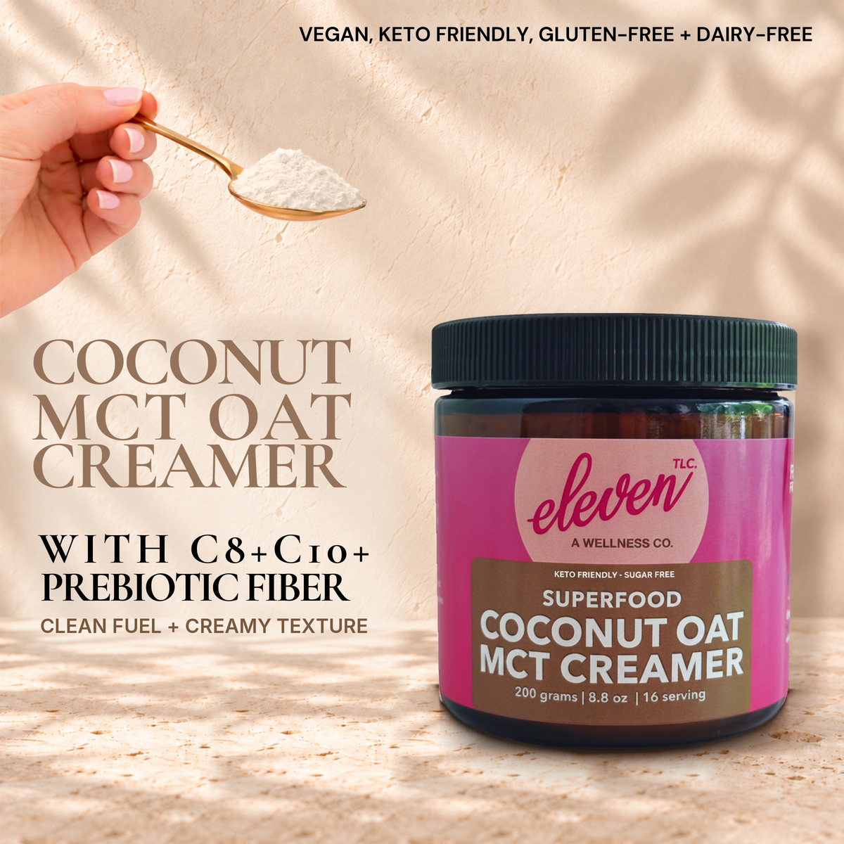 Eleven TLC Coconut Oat MCT Creamer 200g jar on warm travertine beside a hand holding a gold spoon of powder, with C8, C10 and prebiotic fiber text.