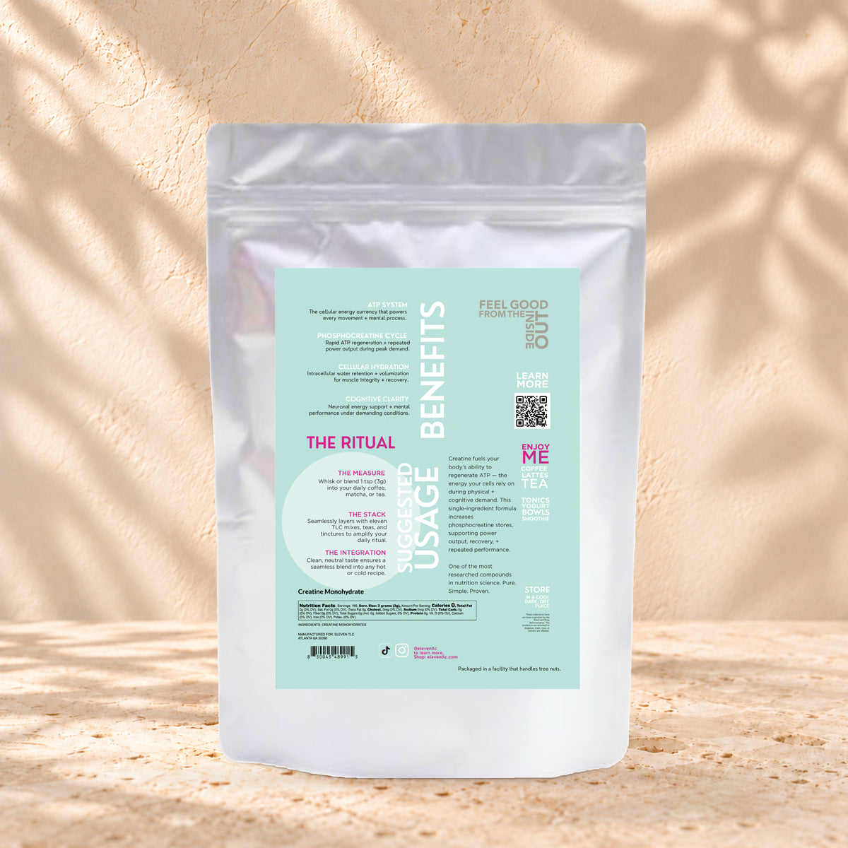 Back view of an Eleven TLC Creatine Monohydrate 500g pouch on warm travertine against a cream plaster wall with botanical shadows.