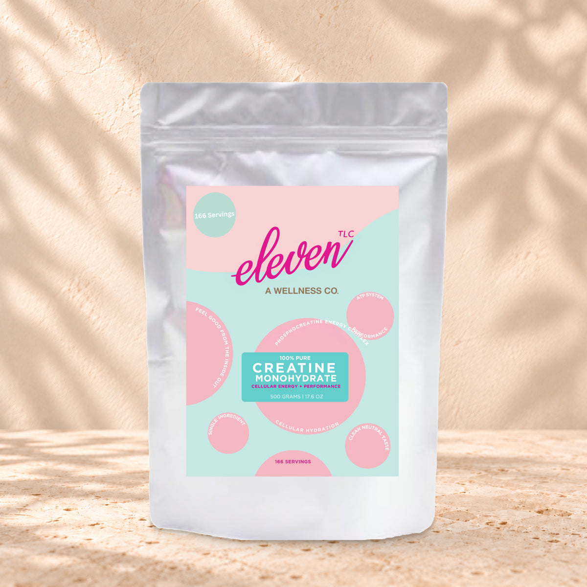 Eleven TLC Creatine Monohydrate 500g stand-up pouch on travertine stone against a warm cream plaster wall, lit from the left with a soft shadow to the right.