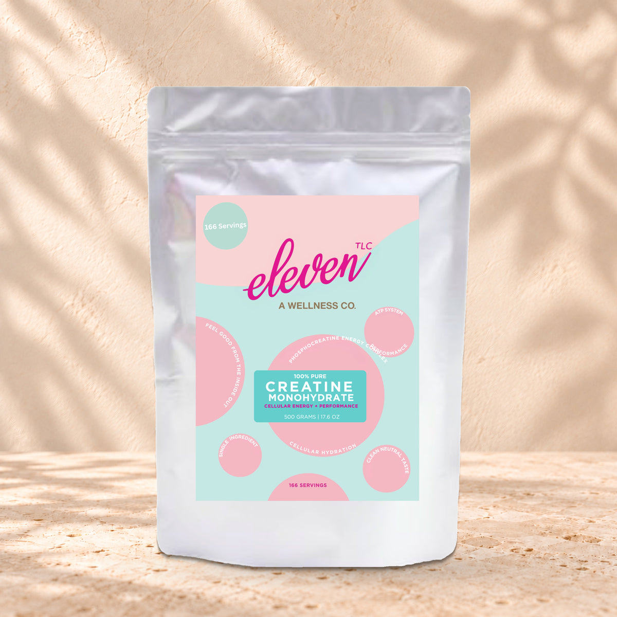 Eleven TLC Creatine Monohydrate 500g stand-up pouch on travertine stone against a warm cream plaster wall, lit from the left with a soft shadow to the right.