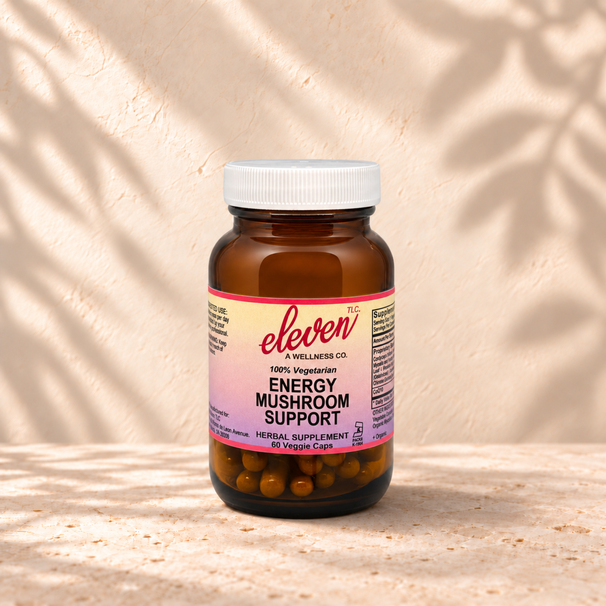 Eleven TLC Energy Mushroom + Adaptogen capsules, 60-count amber glass bottle with pink and yellow label on stone