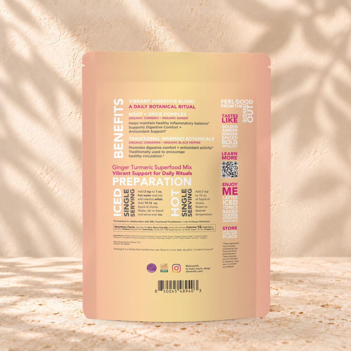 Back view of an Eleven TLC Ginger Turmeric 500g pouch on warm travertine against a cream plaster wall with botanical shadows.