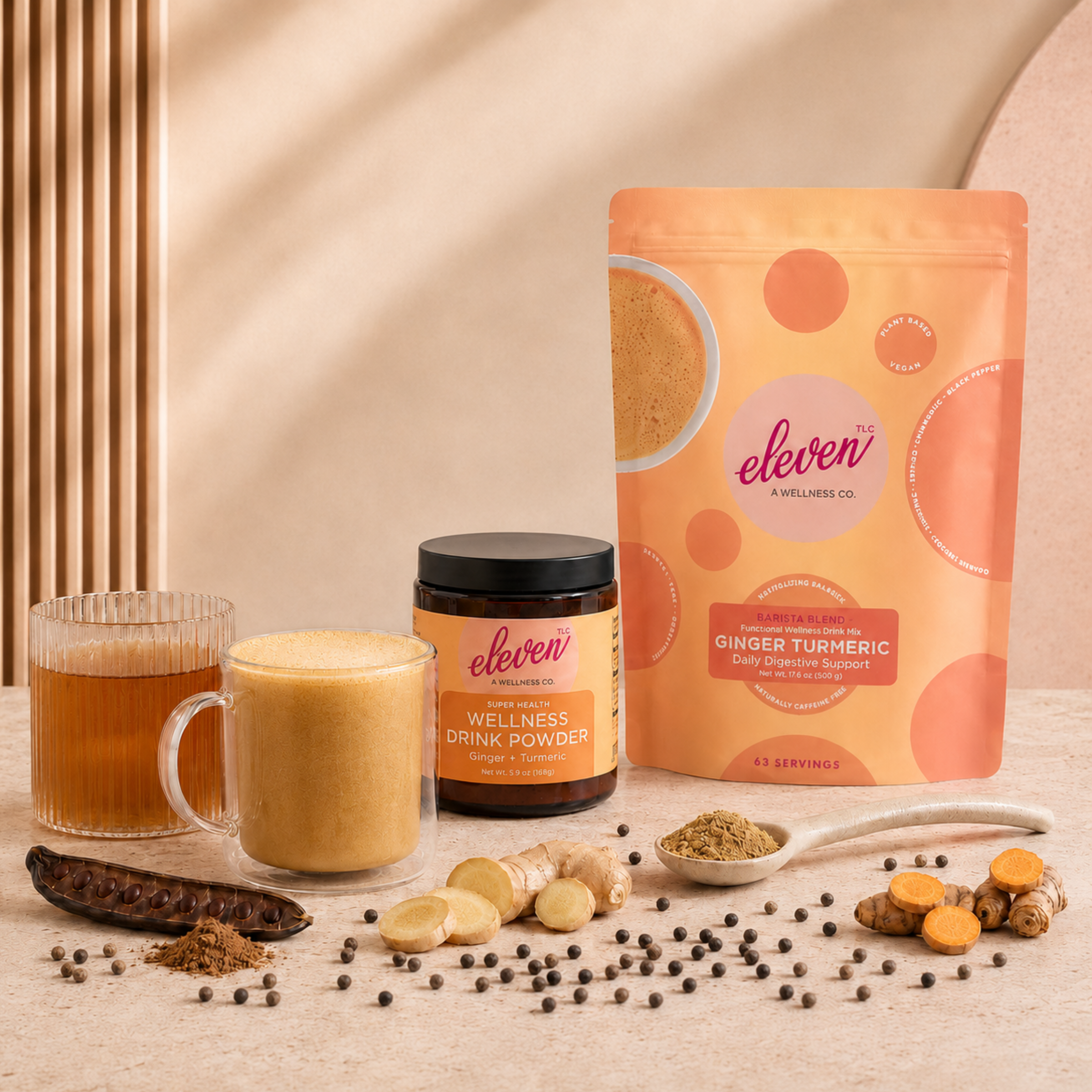 Eleven TLC Ginger Turmeric Barista Blend 500g pouch and amber glass jar, alongside two prepared daily signal beverages in clear mugs, raw ginger root, whole turmeric, carob pods, and black peppercorns.