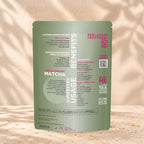 Back view of an Eleven TLC Japanese Matcha 500g pouch on warm travertine against a cream plaster wall with botanical shadows.
