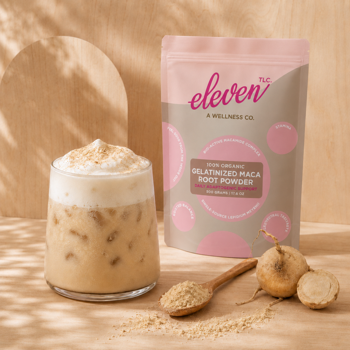 Iced maca latte with an Eleven TLC Organic Gelatinized Maca Root Powder 500 g bag, maca roots and powder on warm natural wood.