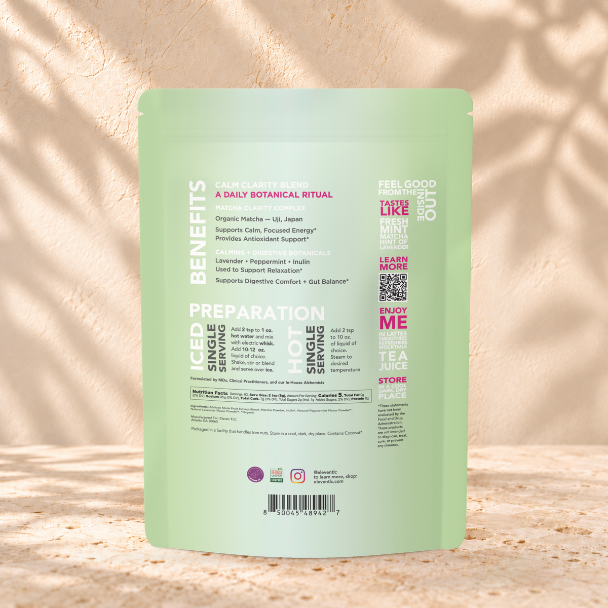 Back view of an Eleven TLC Minty Lavender Matcha 500g pouch on warm travertine against a cream plaster wall with botanical shadows.