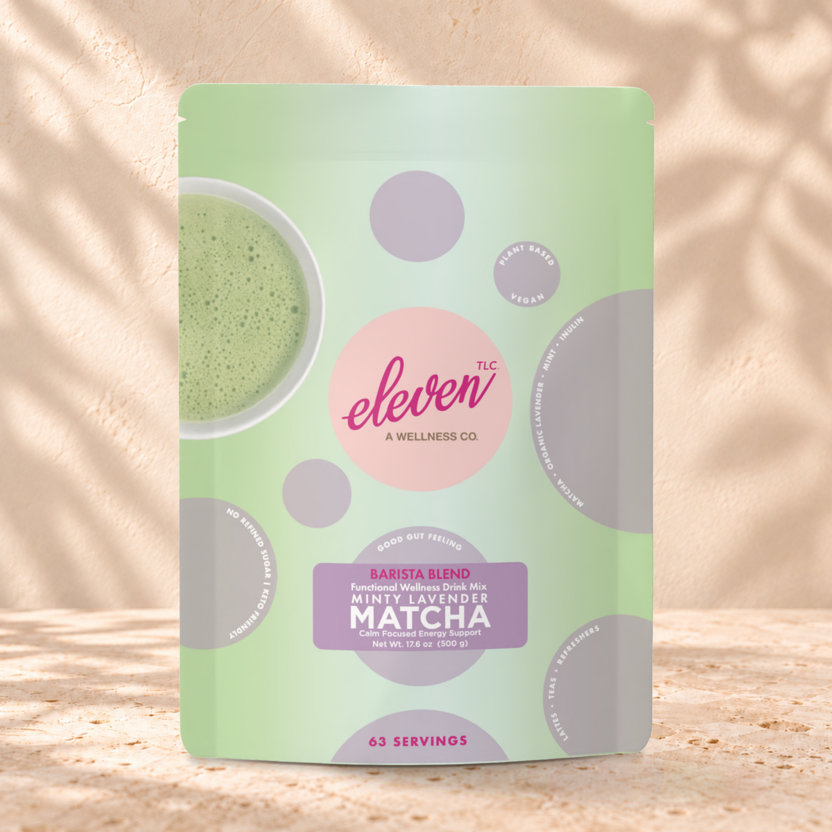 Eleven TLC Minty Lavender Matcha 500g pouch standing on a travertine ledge against warm plaster, with a contact shadow beneath its base and a soft shadow to the right.