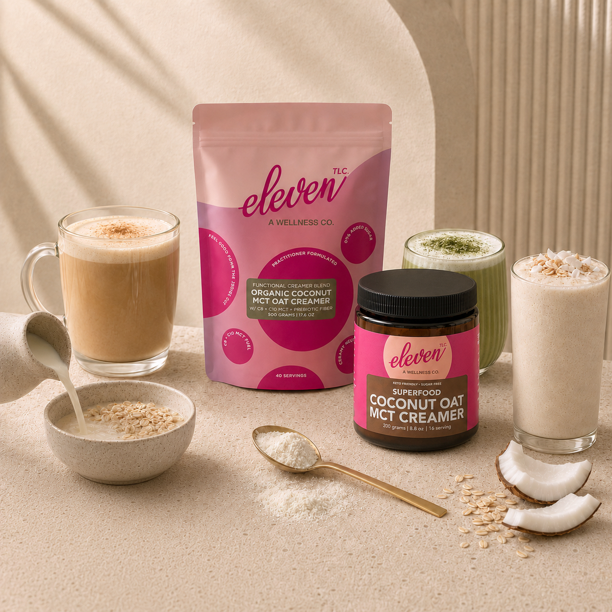 Eleven TLC Coconut MCT Oat Creamer 500g stand-up pouch and amber glass jar on a stone table with a matcha latte, a coffee, a smoothie and a bowl of oatmeal topped with berries, coconut flakes and oats.