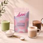 Eleven TLC organic MCT oil powder 500g pouch with a green matcha latte, a cappuccino, a mocha, a bowl and gold spoon of white powder and a coconut in warm window light.
