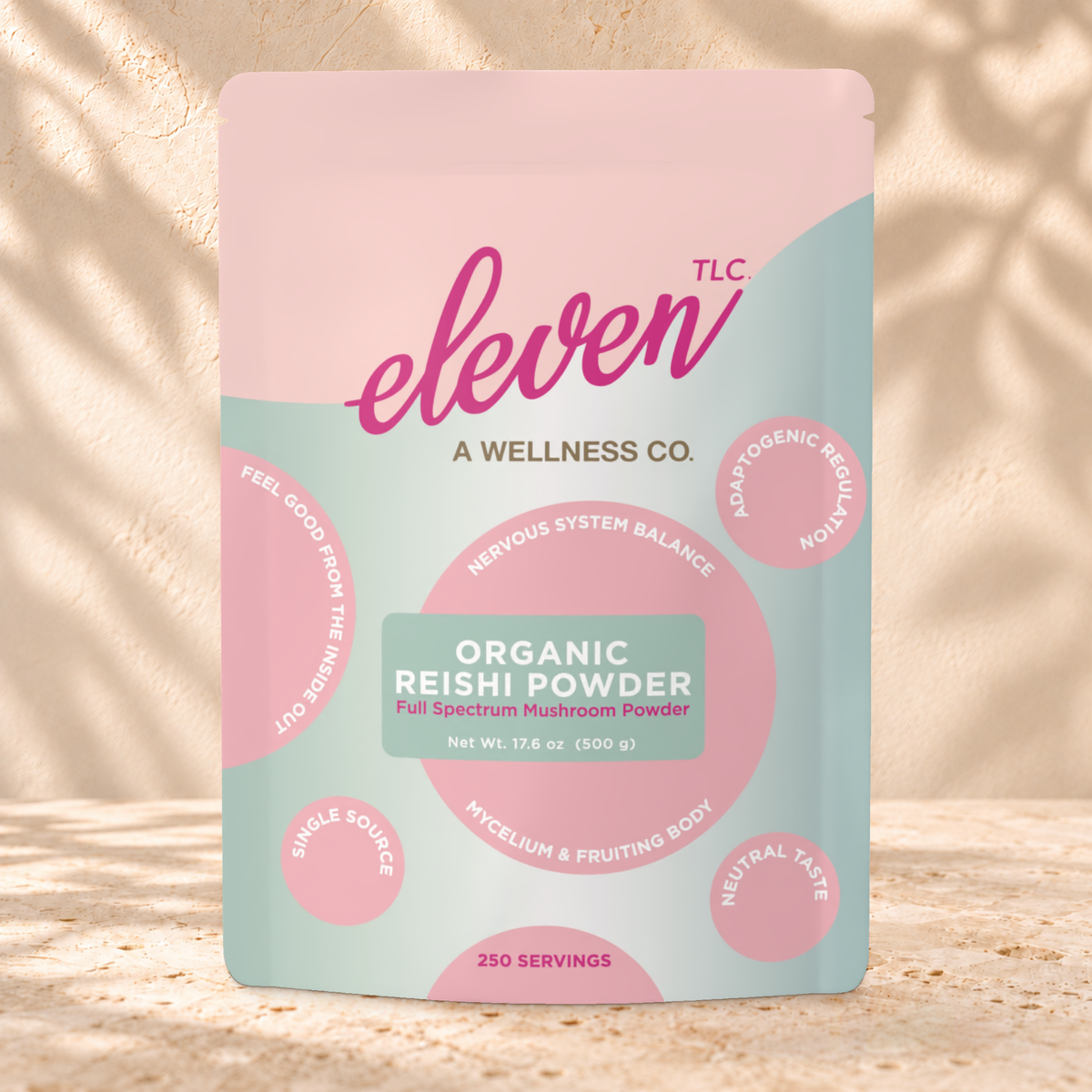 Front view of an Eleven TLC Reishi Mushroom Powder 500g pouch on warm travertine against a cream plaster wall with botanical shadows.