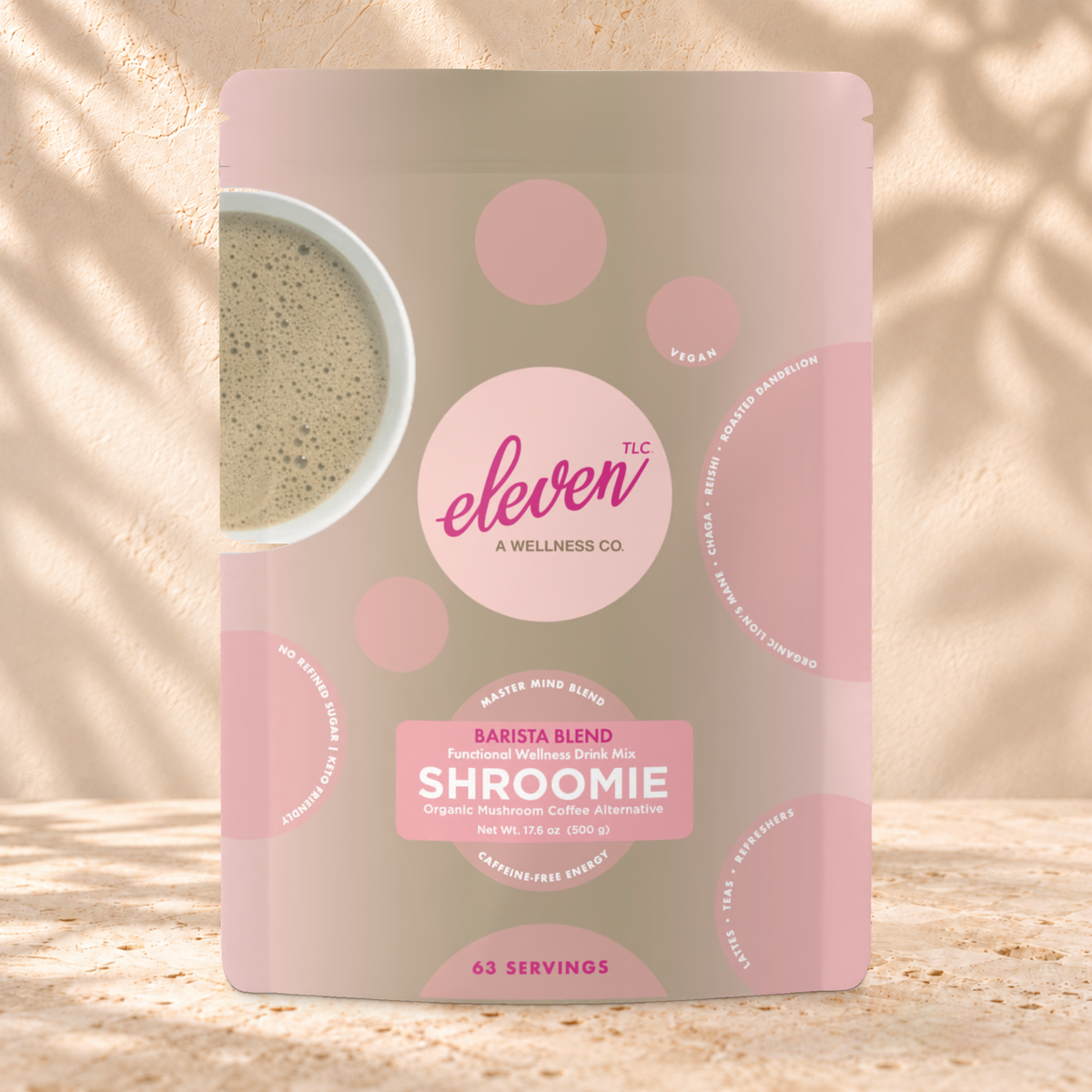 Front view of an Eleven TLC Shroomie 500g pouch on warm travertine against a cream plaster wall with botanical shadows.