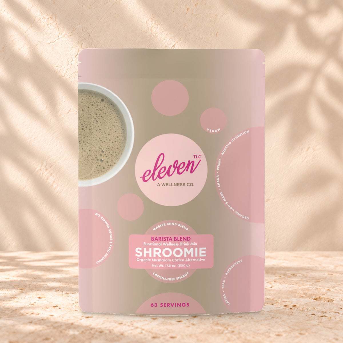 Eleven TLC Shroomie 8-Adaptogen Blend 500g stand-up pouch on travertine stone against a warm cream plaster wall, lit from the left with a soft shadow to the right.