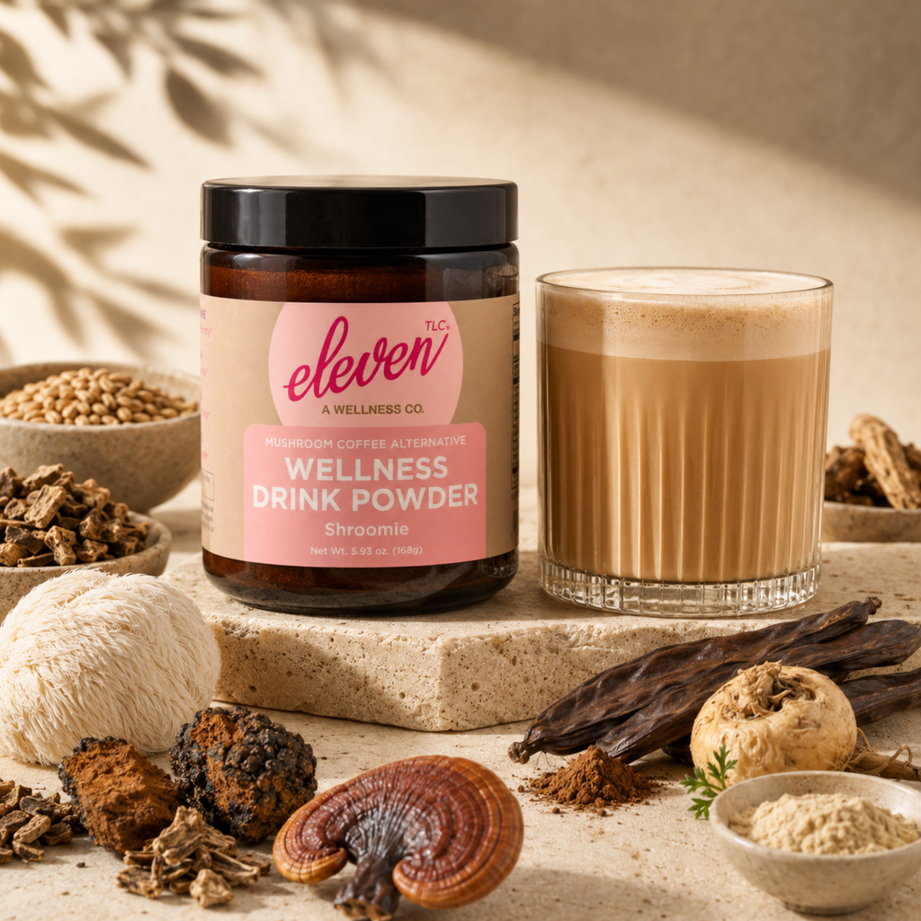 Eleven TLC Shroomie wellness drink powder jar with prepared latte and raw functional ingredients on a wooden surface.